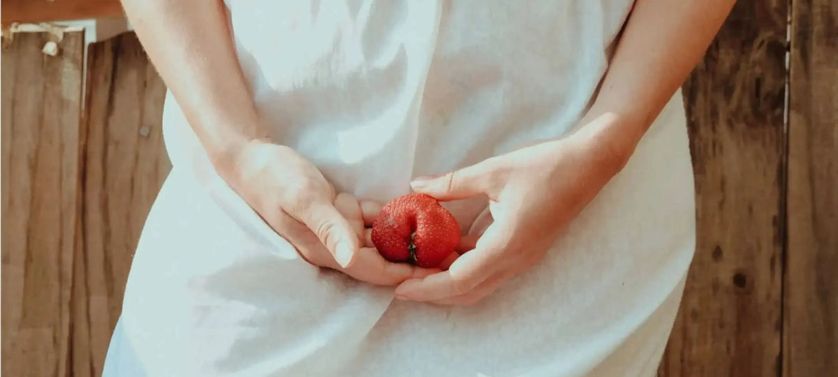 Eine Frau hält eine Tomate in Vulvaform.