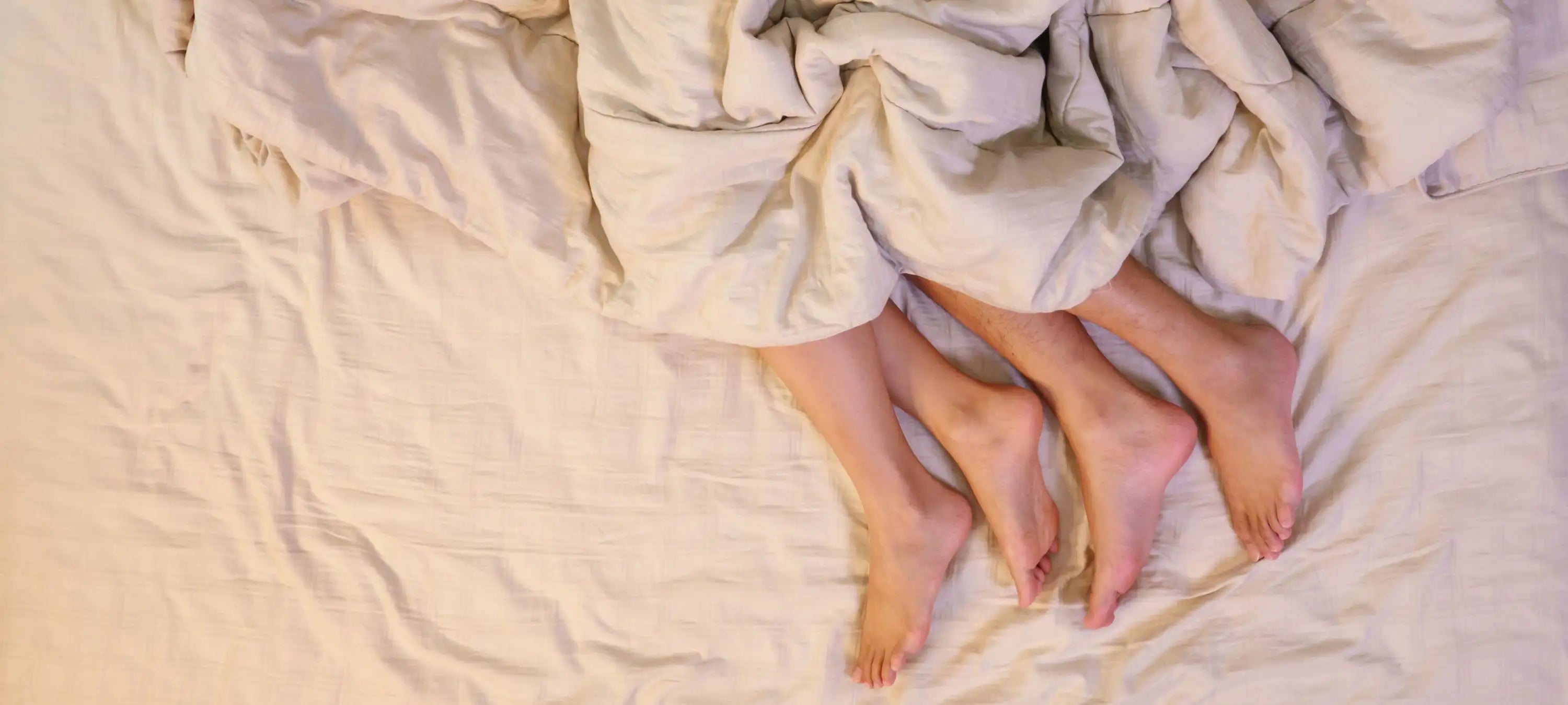 man sieht sie Füße zweier Personen unter der Decke hervor ragen.