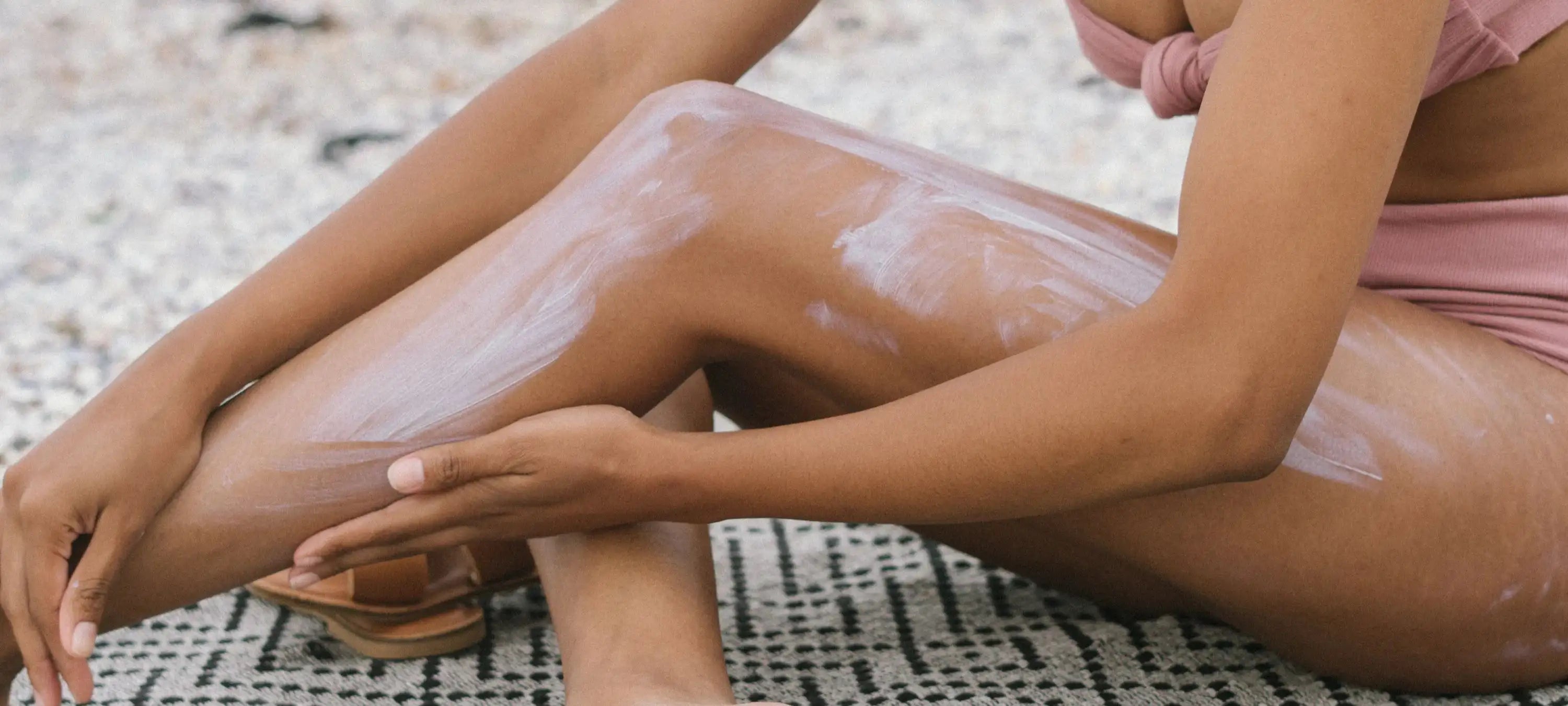 Eine Frau pflegt ihr gebräuntes Bein mit einer natürlichen Creme.