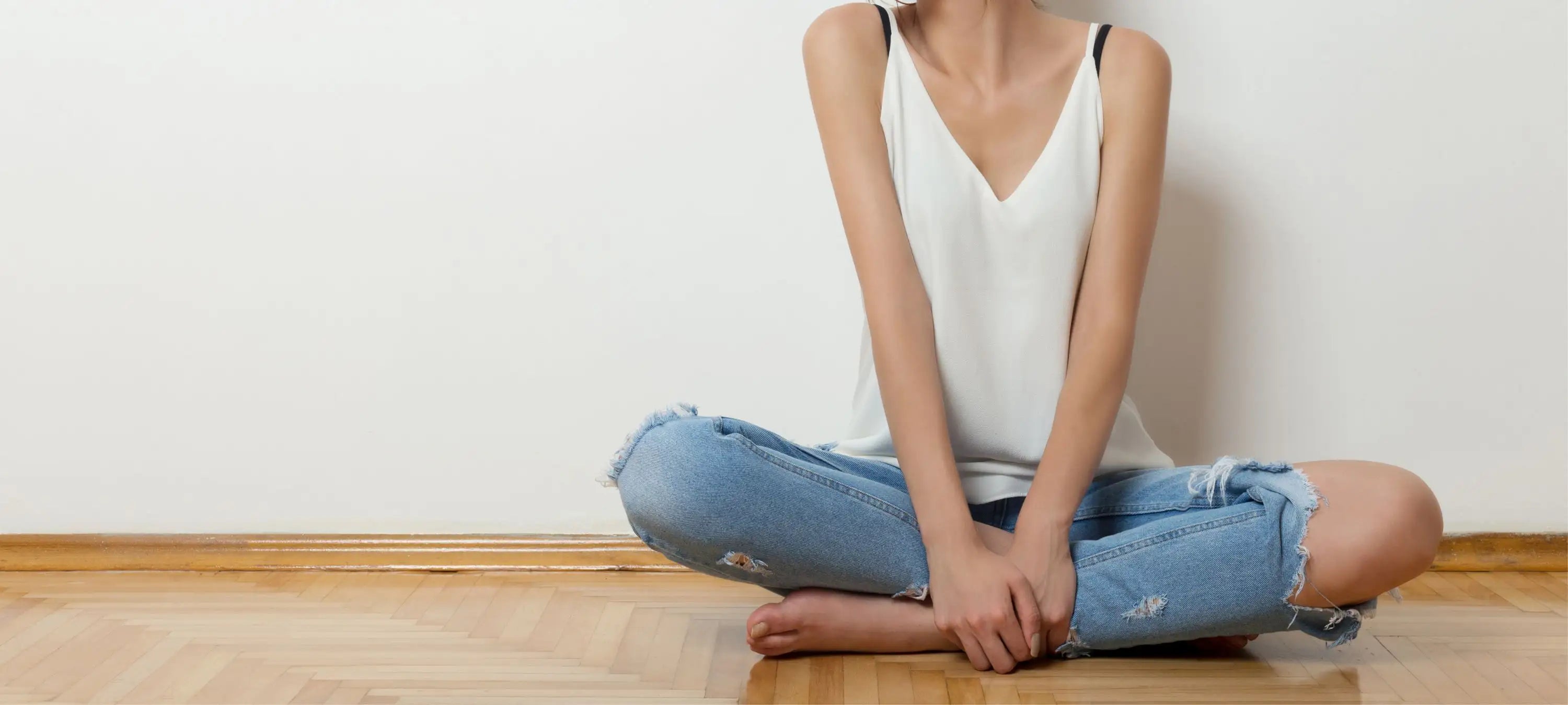 Eine Frau sitzt imSchneidersitz. Scheidenpilz kann sehr lästig sein und im Alltag einschränken.