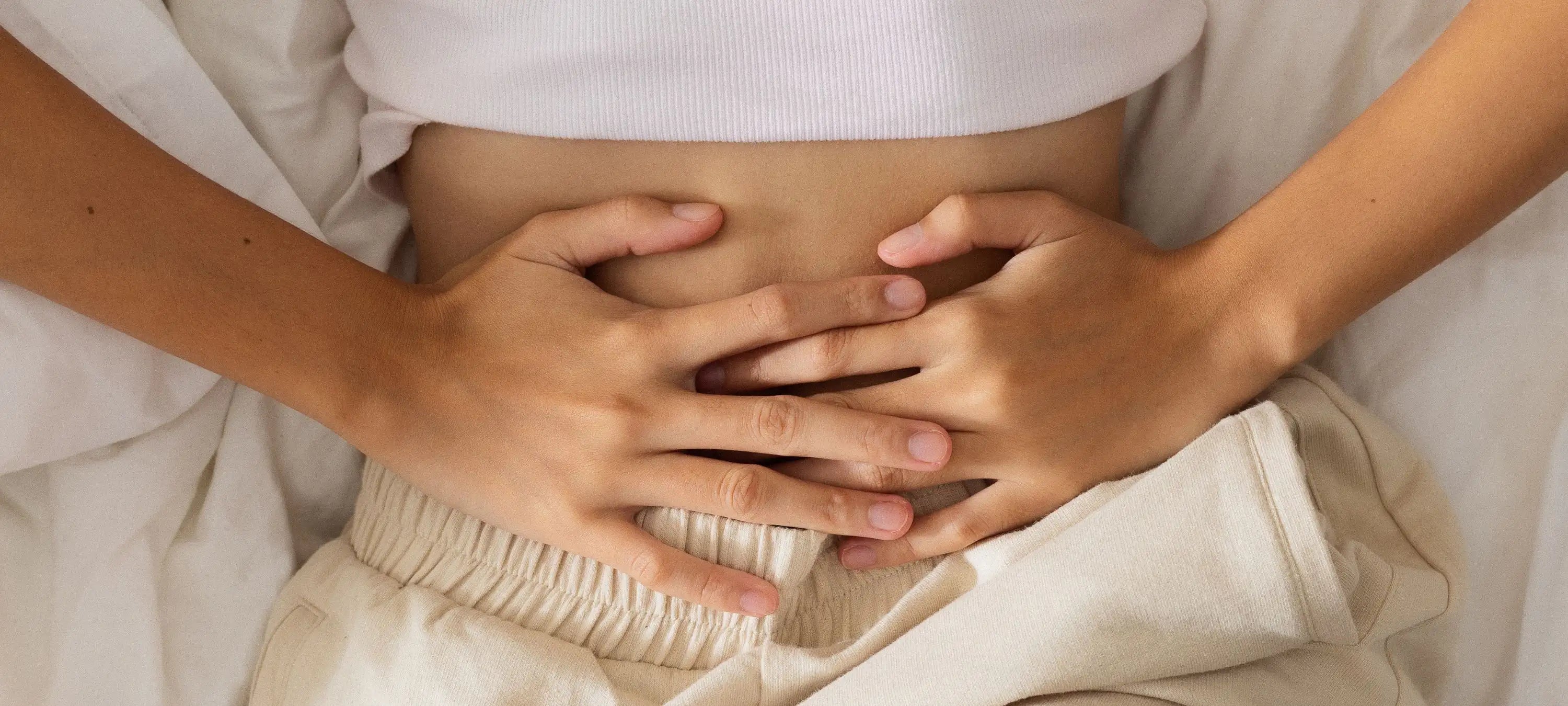 Eine Frau mit Verdauungsproblemen ist abgebildet, wobei ein Zyklus Workshop Ernährung bei periodenbedingten Verdauungsproblemen helfen kann.