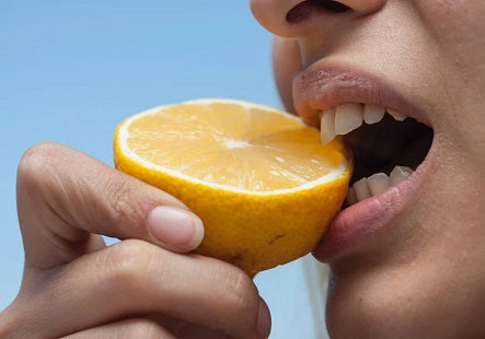 Person beißt in Zitrone. Tipps und Informationen, wie du dein Immunsystem stärken kannst.