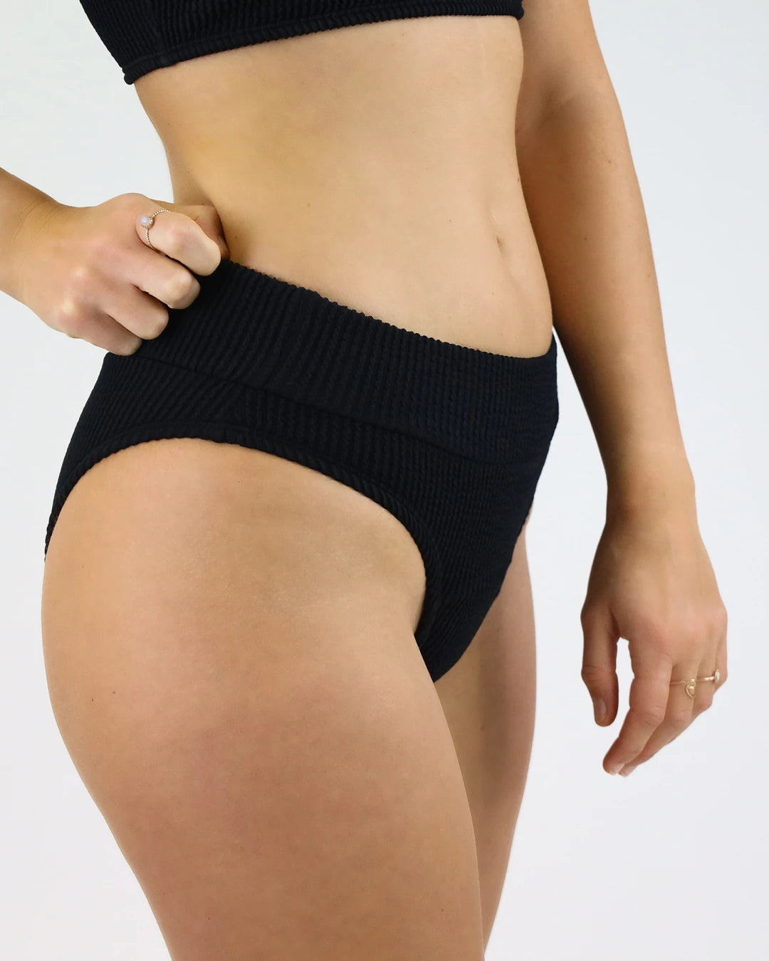 Schwarze Bikinihose mit hohem Bund und gerippter Struktur, seitlich gezeigt. Figurbetonter, bequemer Schnitt – ideal für Strand und Pool.