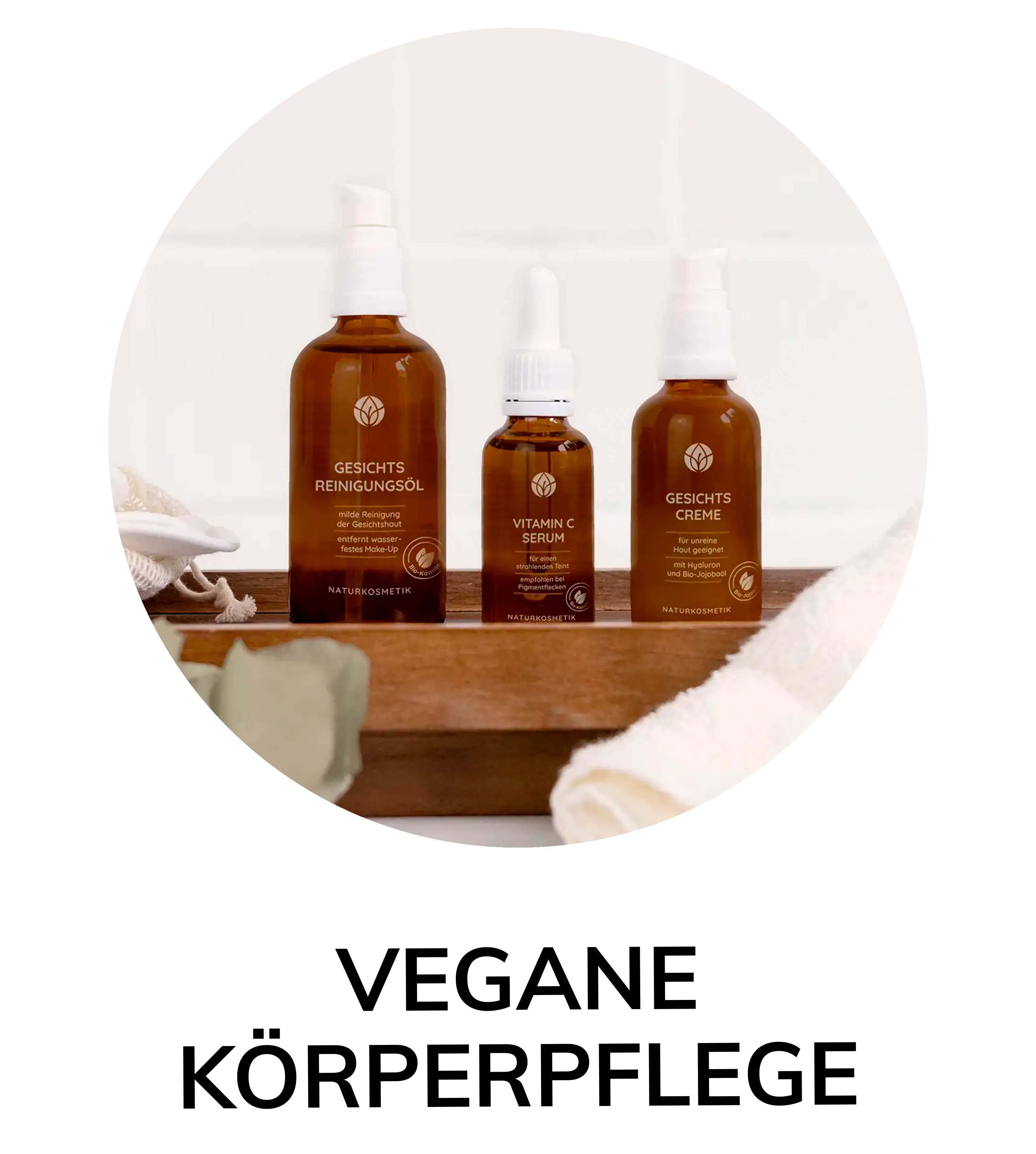 Drei braune Glasflaschen mit veganer Naturkosmetik: Gesichtsöl, Vitamin-C-Serum und Gesichtscreme auf Holzablage mit Handtuch.