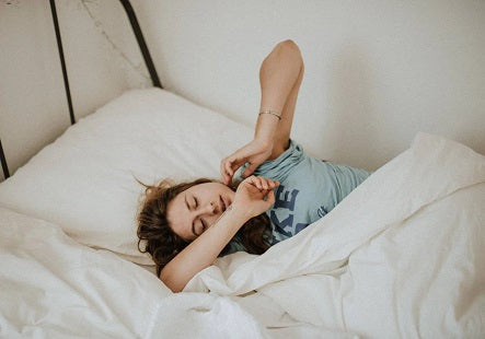 Eine Frau streckt sich im Bett. Viele Frauen leiden unter Eisenmangel und haben mit Müdigkeit zu kämpfen.