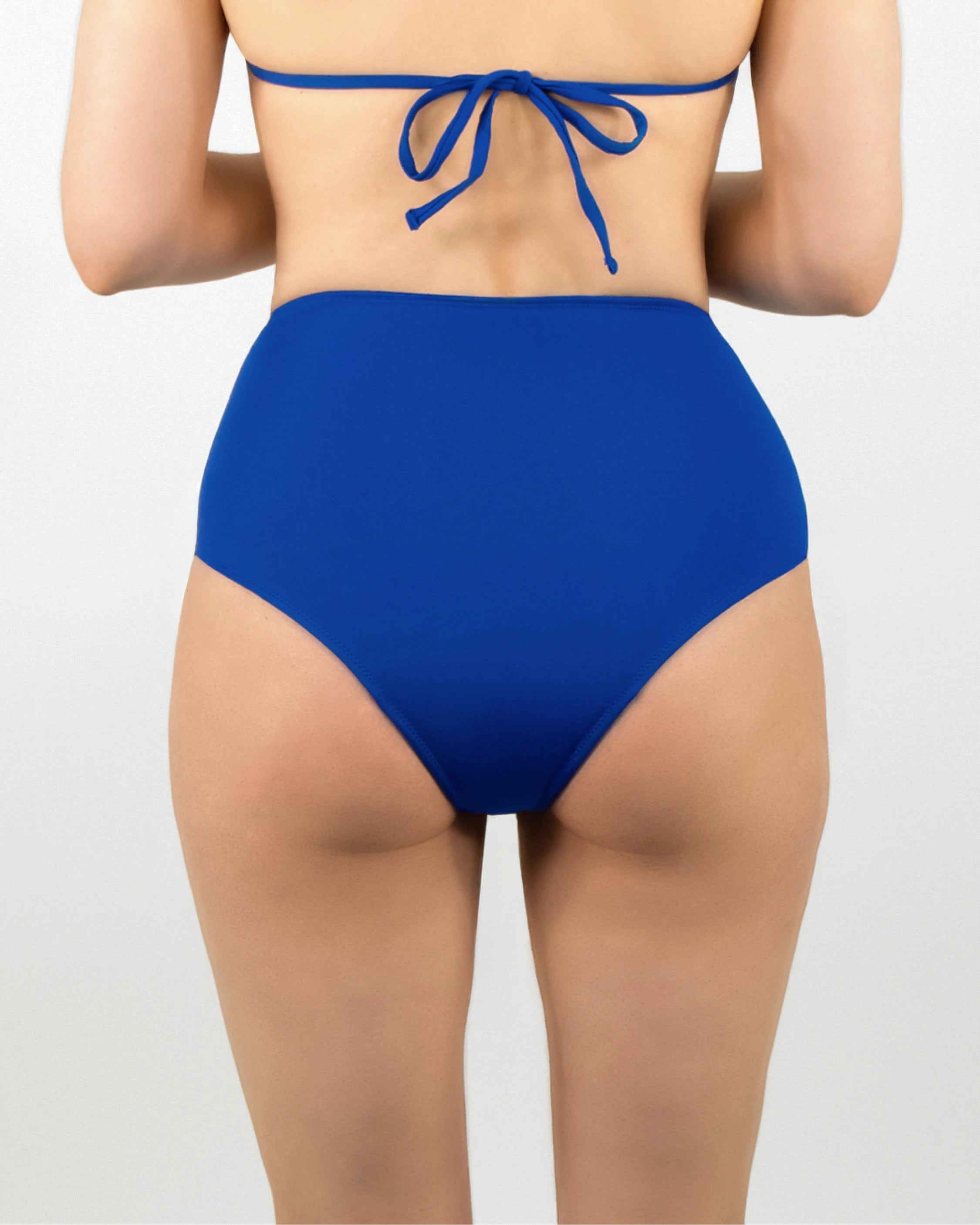 Model vor weißer Leinwand mit dem Rücken zur Kamera und trägt die Perioden Bikinihose High Waist in royalblau von MYLILY.