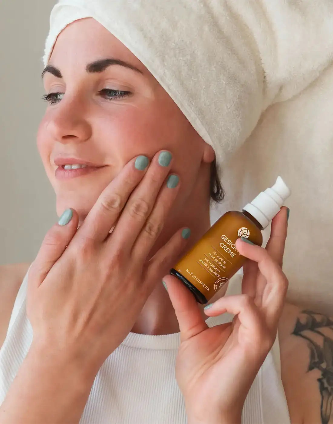 Eine lächelnde Frau cremt ihr Gesicht mit der Gesichts Creme von MYLILY ein.