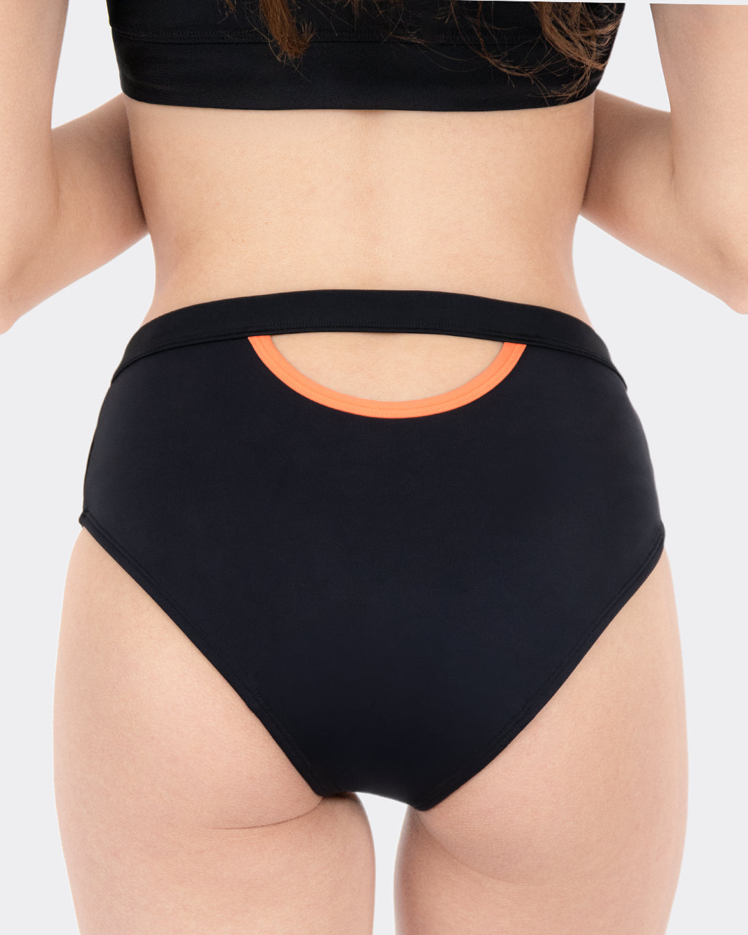 Rückansicht MYLILY Perioden-Bikinihose schwarz mit auffälligem Cut-Out und orangem Akzentring am Bund, kombiniert mit schwarzem Crop-Bikinioberteil – Periodenbademode mit Stil