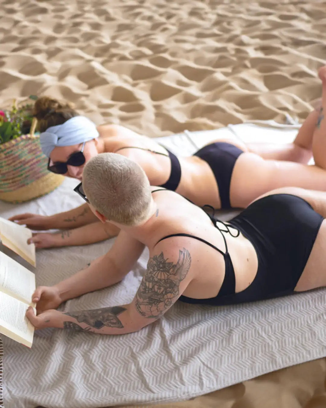 Zwei Frauen am Strand in unserem Periodenbadeanzug Rückenfrei. Das schwarze Design schmeichelt jeder Figur.