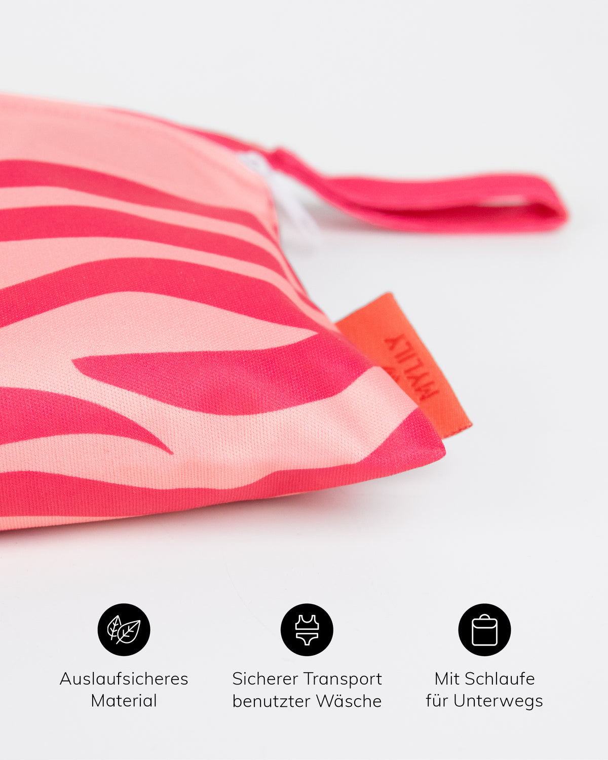 Nahaufnahme der pinken MYLILY Wetbag mit Zebramuster, Schlaufe und Markenetikett. Icons darunter: auslaufsicheres Material, sicherer Transport benutzter Wäsche, mit Schlaufe für unterwegs.