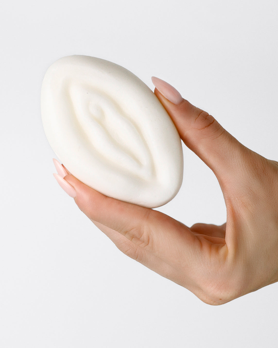 Frau hält Naturkosmetikprodukte Seife in Vulvaform für die Intimreinigung.