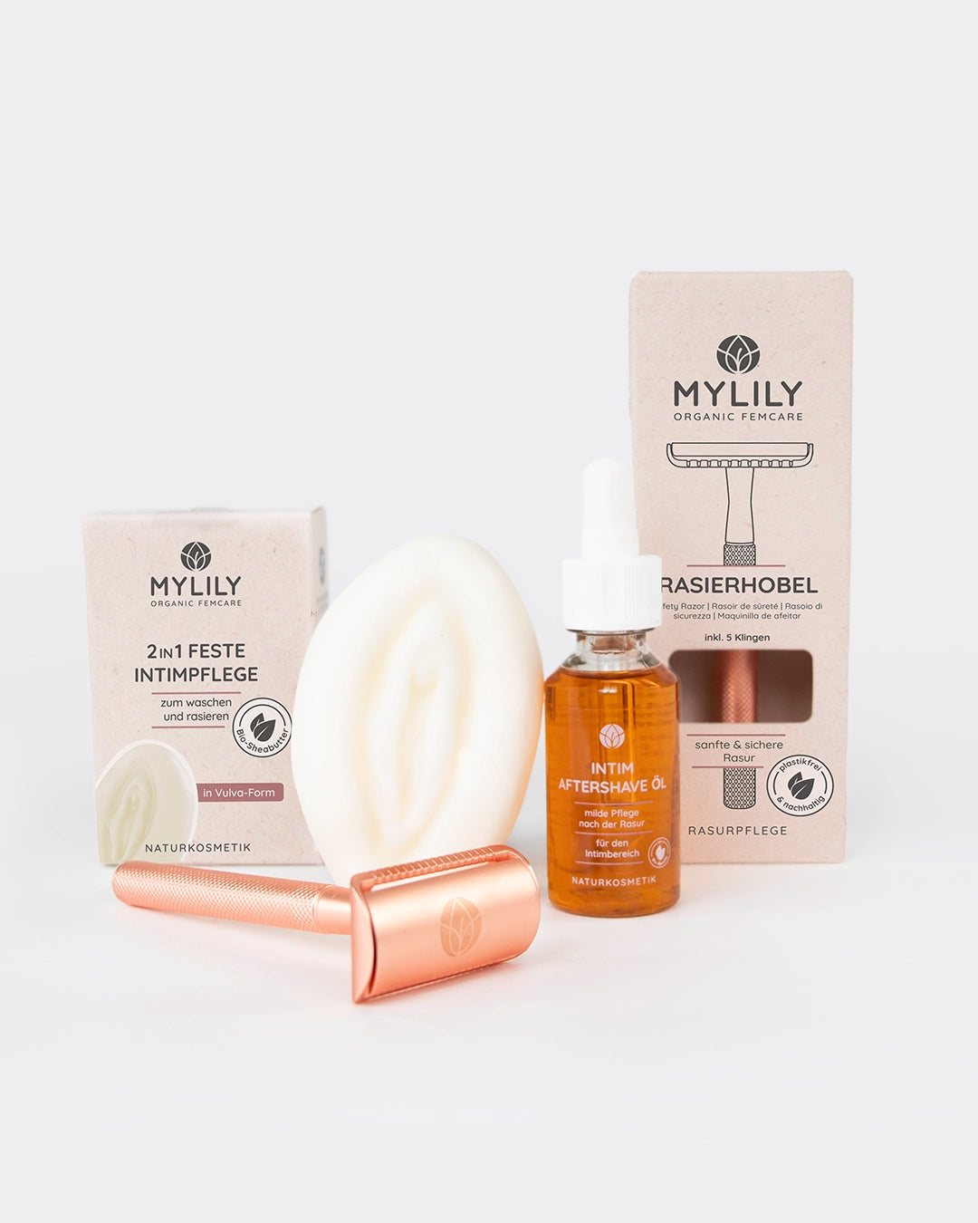 Das Vulva Care Set Produkte aufgereiht mit Rasierhobel, Aftershave Öl und Vulva Waschstück.