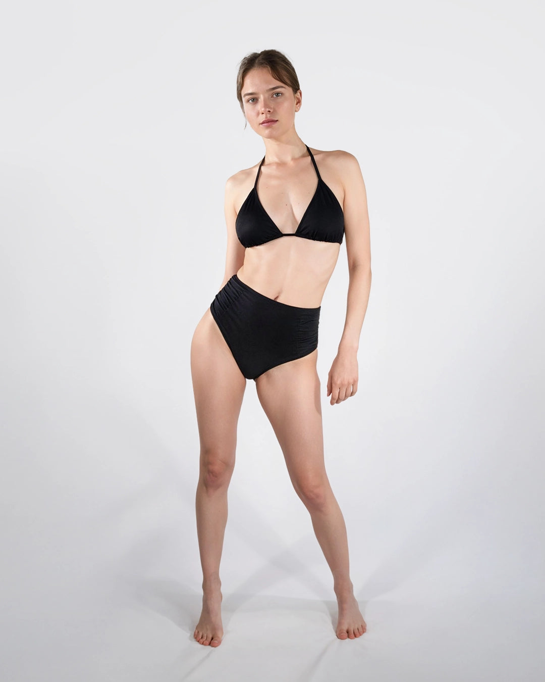 Eine junge Frau posiert vor einer Leinwand in der Bikini Hose High Waist mit Raffung.