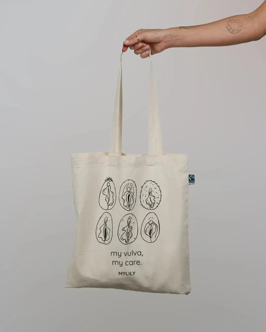 My vulva, my care Jutebeutel aus Bio-Baumwolle von vorne in einer Hand. Aus 100% Baumwolle mit langen Henkeln.