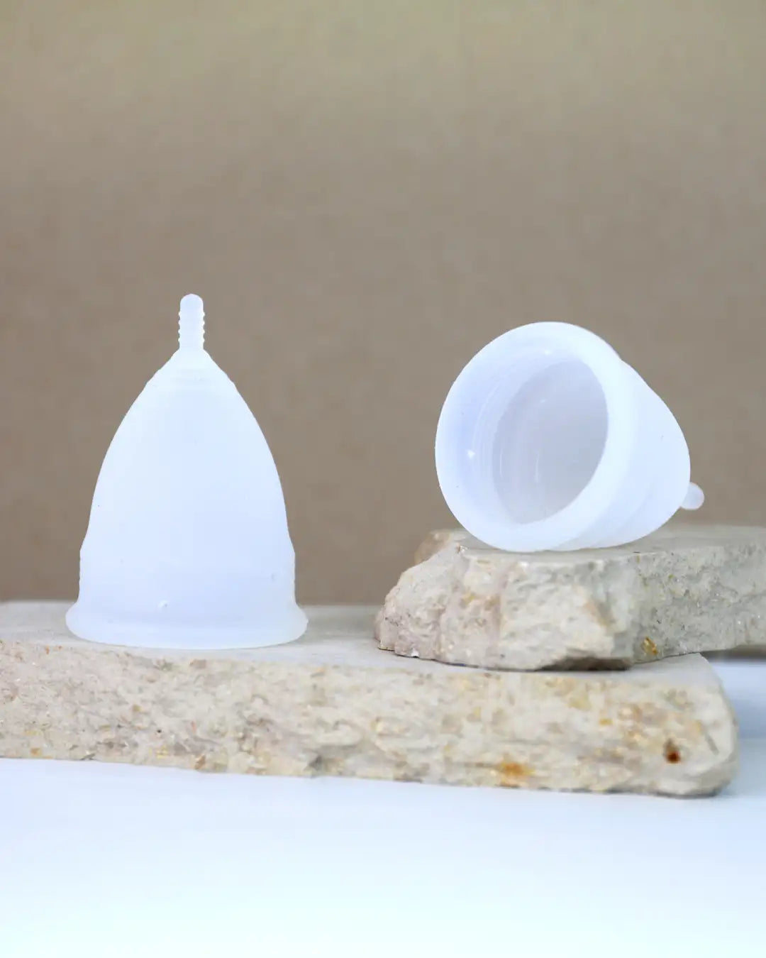 Die verschiedenen Größen der Menstruationstasse mit Verpackung auf einem Holzblock