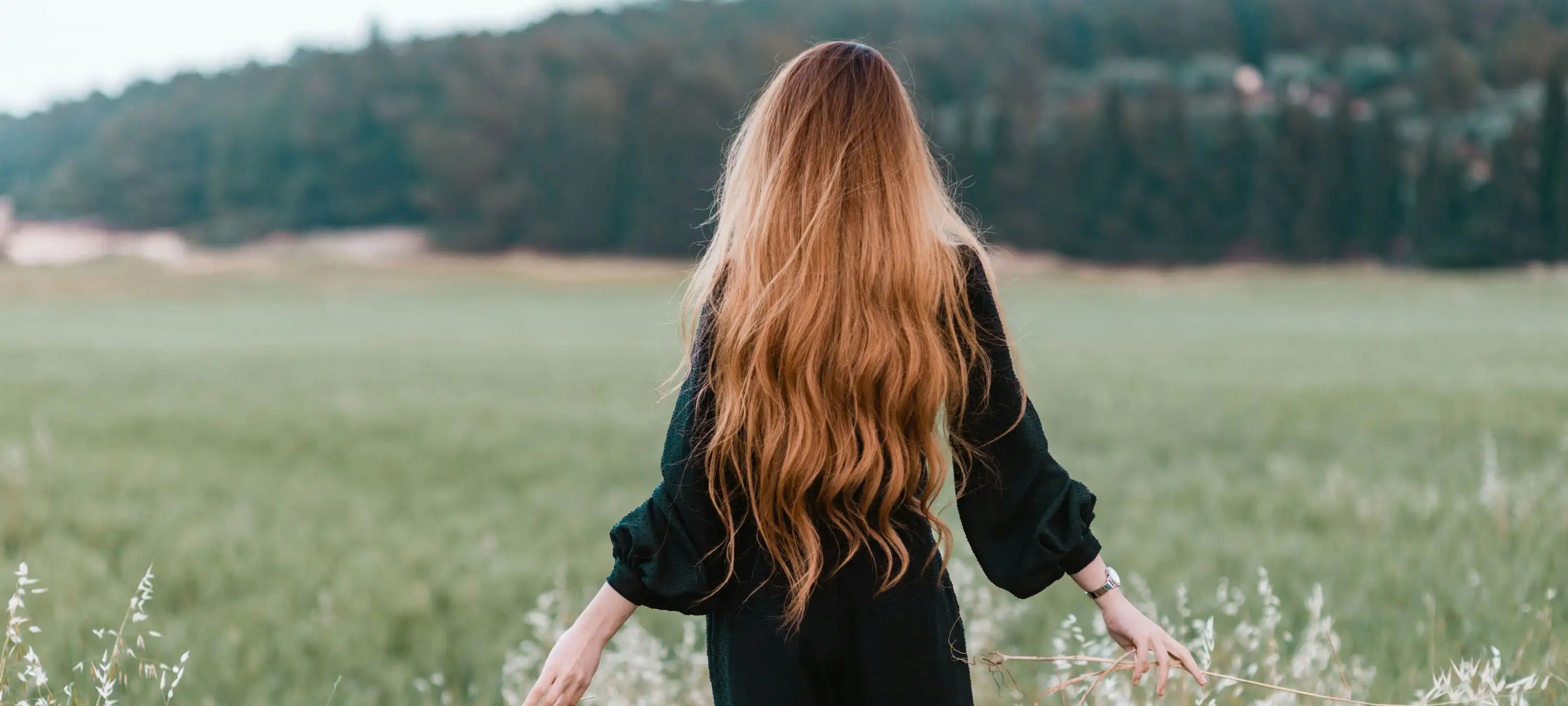 Eine Frau in der Natur mit gesundem, langem, welligen Haar.