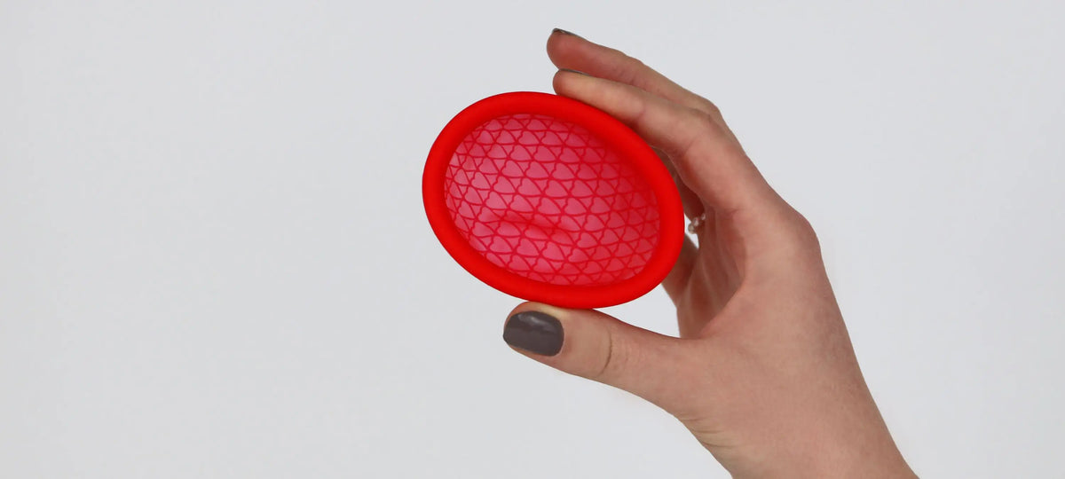 Eine Frau hält eine Menstruationsdisk oder auch Menstruationsscheibe in die Kamera.