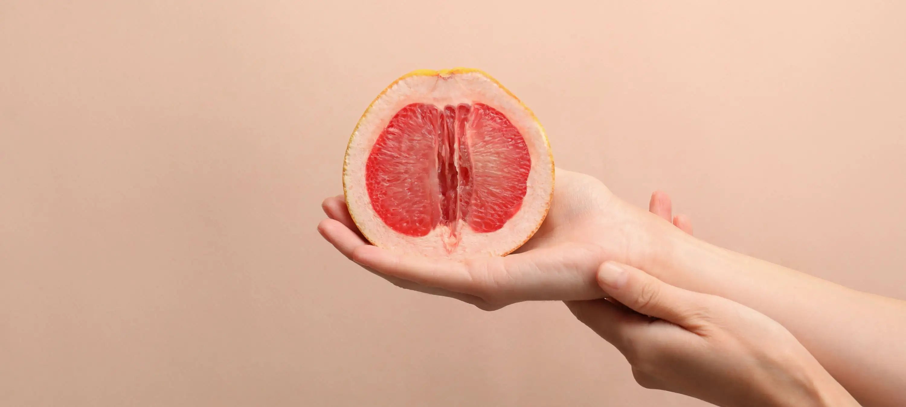 Eine Grapefruit liegt in der Hand einer Frau und symbolisiert die weiblichen Geschlechtsorgane.