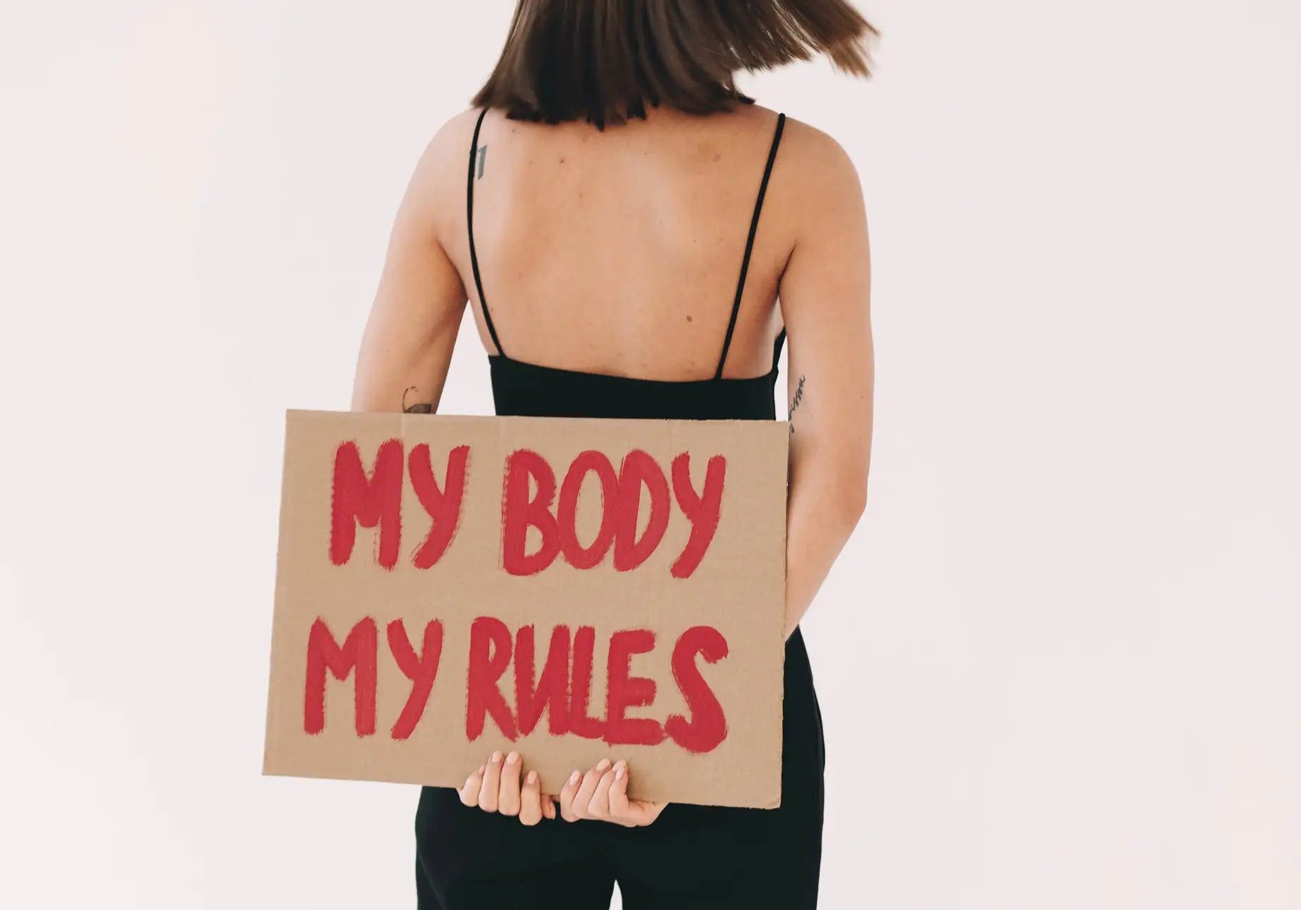 Frau mit Demoschild: my body my rules. MYLILY setzt sich für Empowerment von Frauen ein. Sei wie du willst.
