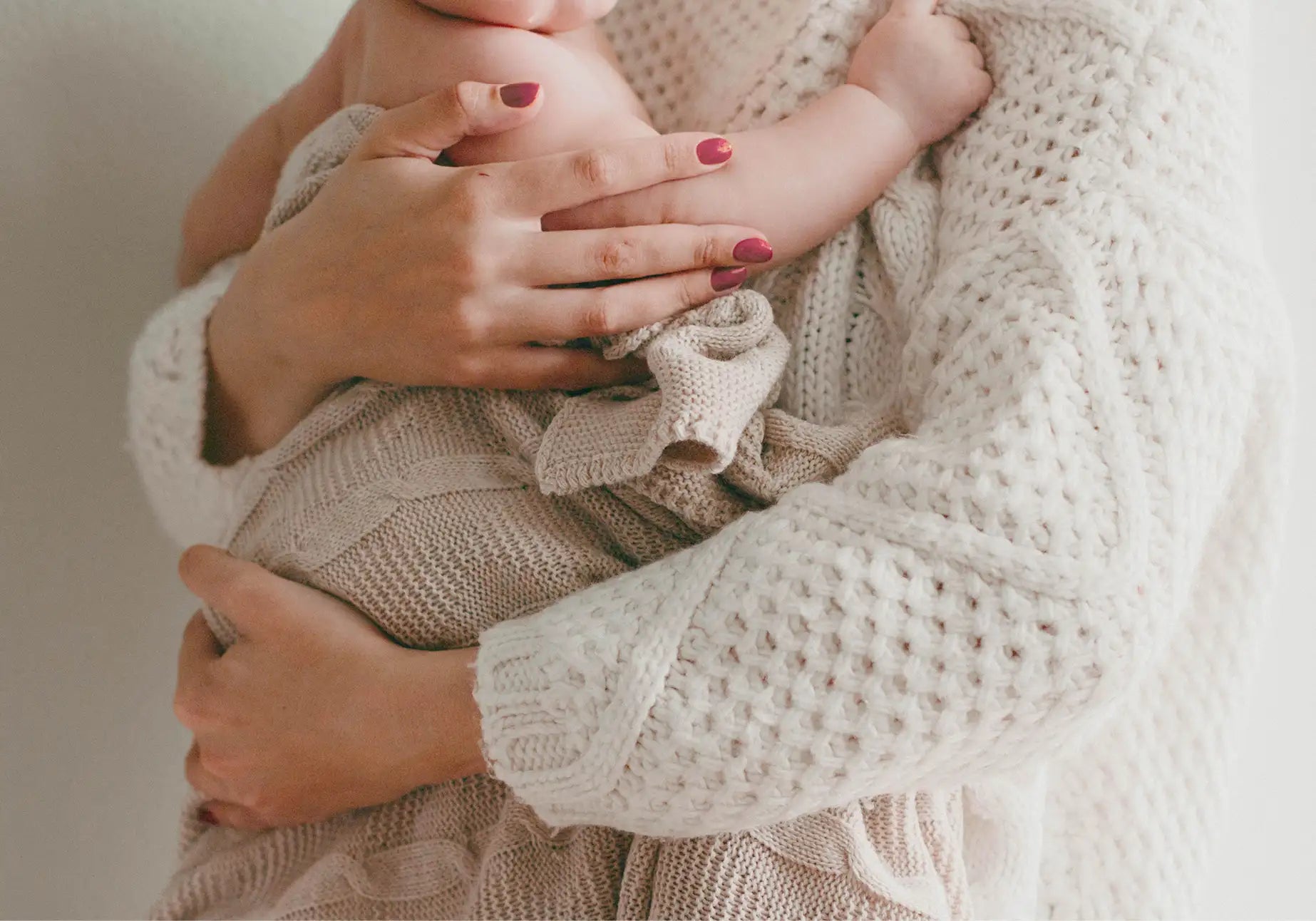 Eine Person hält ein Baby. Informationen zum Thema Mamaliebe, Schwangerschaft und die Bedürfnisse von Mamas.