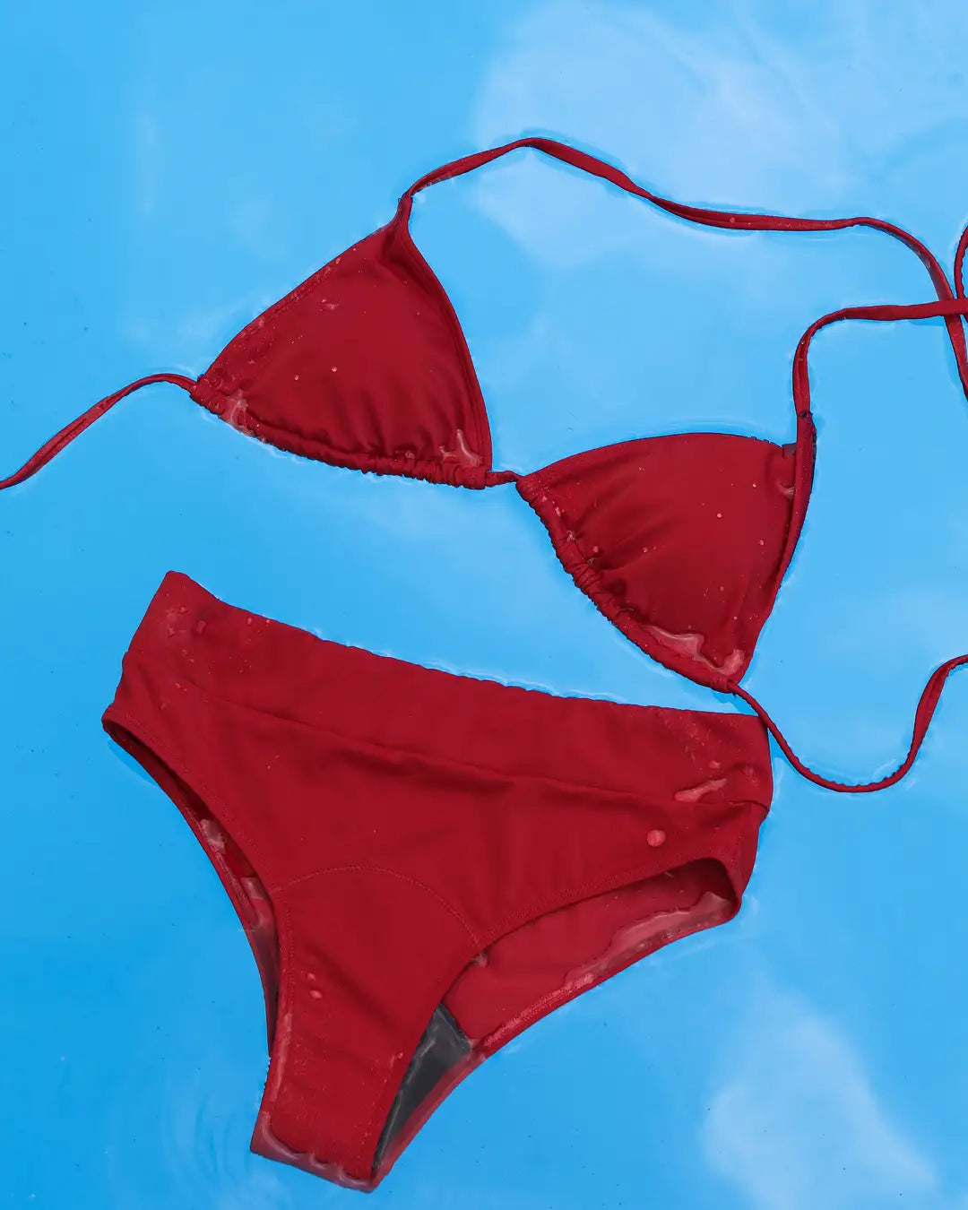 Hagebuttefarbenes Triangel Bikini Oberteil und passende Hose treiben in Poolwasser. #farbe_hagebutte