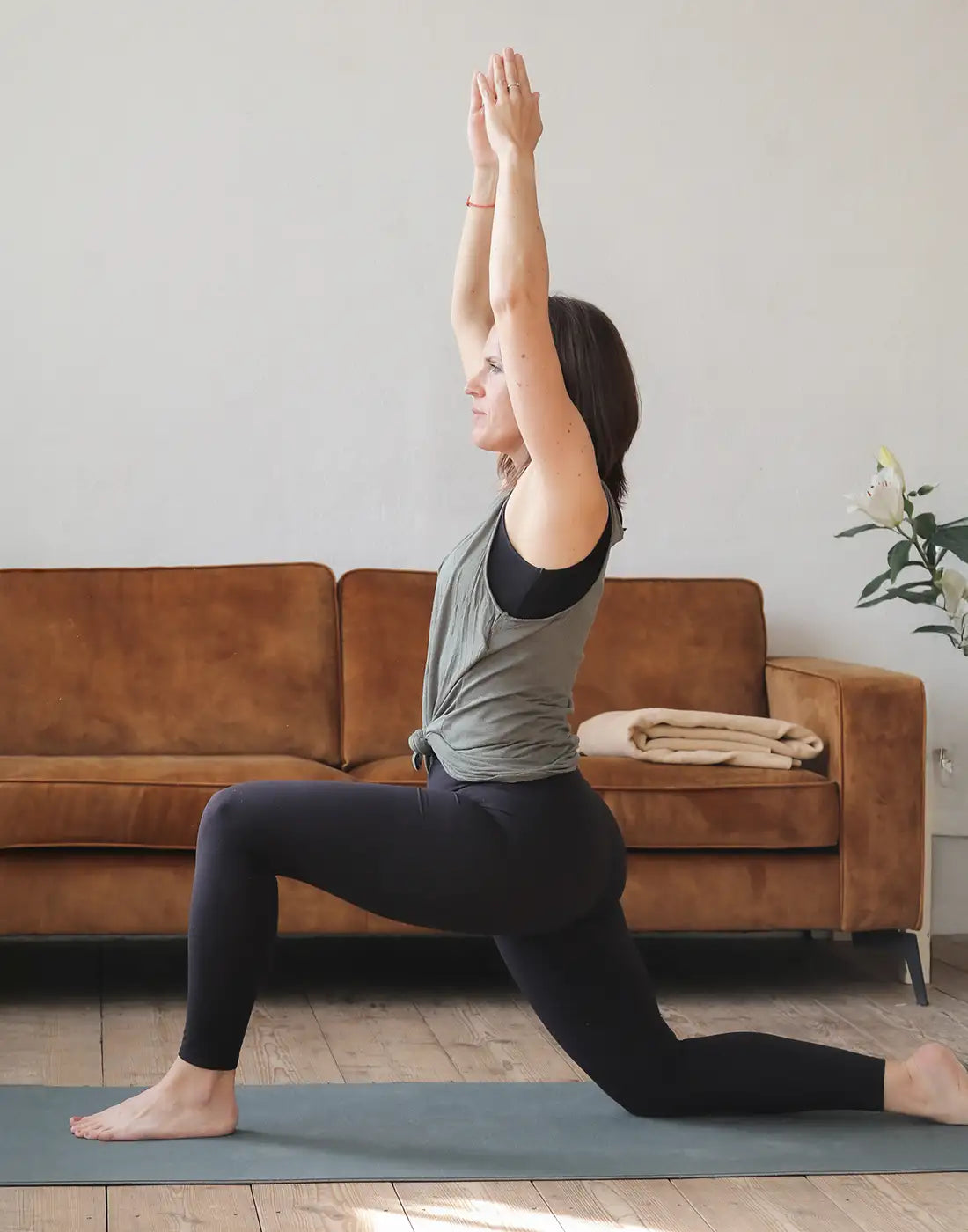 Eine Frau hält eine Yoga Pose auf einer Yogamatte und schaut konzentriert in die Ferne.