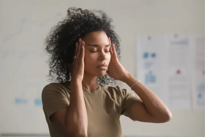 Frau mit Kopfschmerzen massiert Seiten ihres Kopfes mit Handflächen