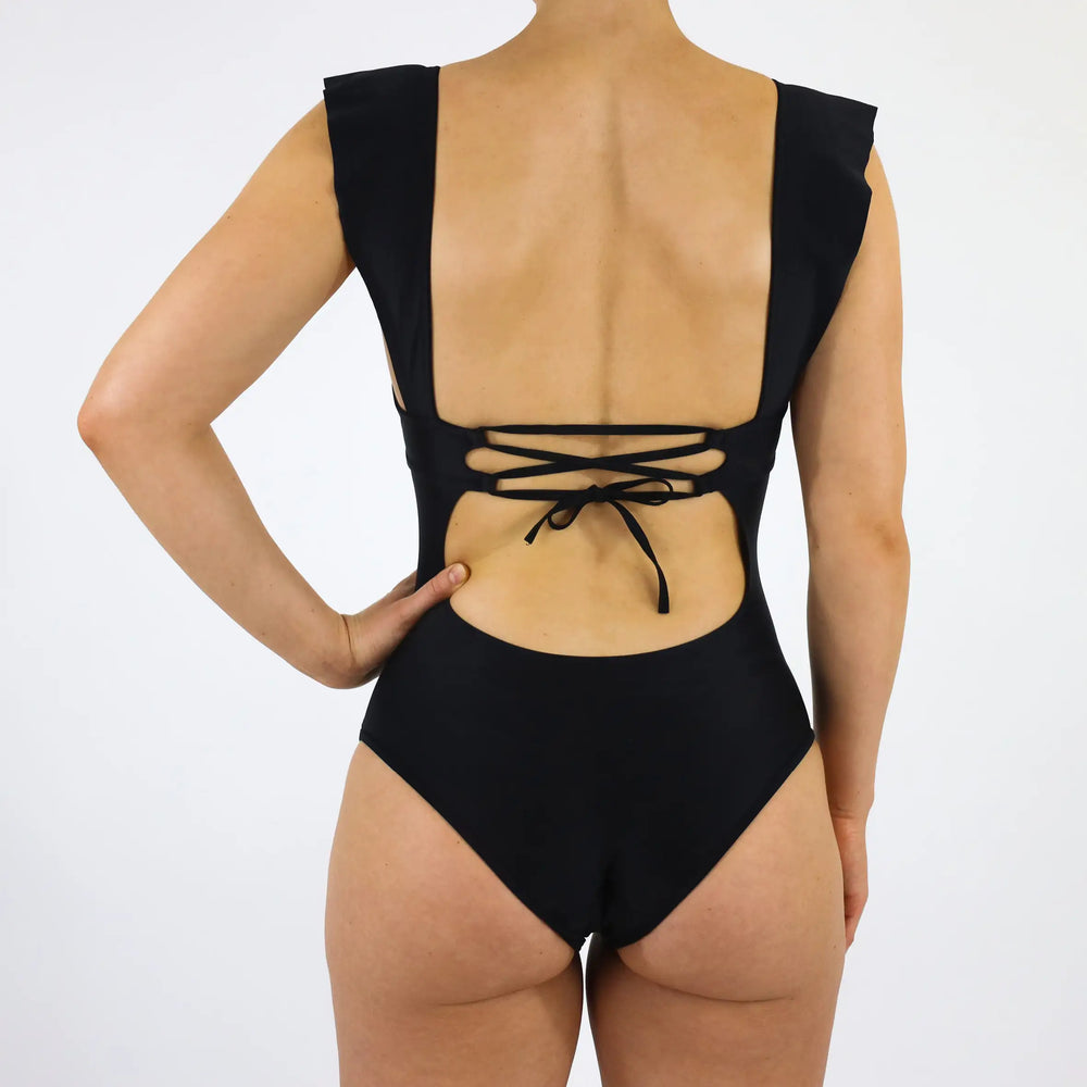 Der elegante Schnitt des Badeanzugs mit Rüschen hat einen schönen Rückenausschnitt, der mit verstellbaren Bändern individualisierbar ist.