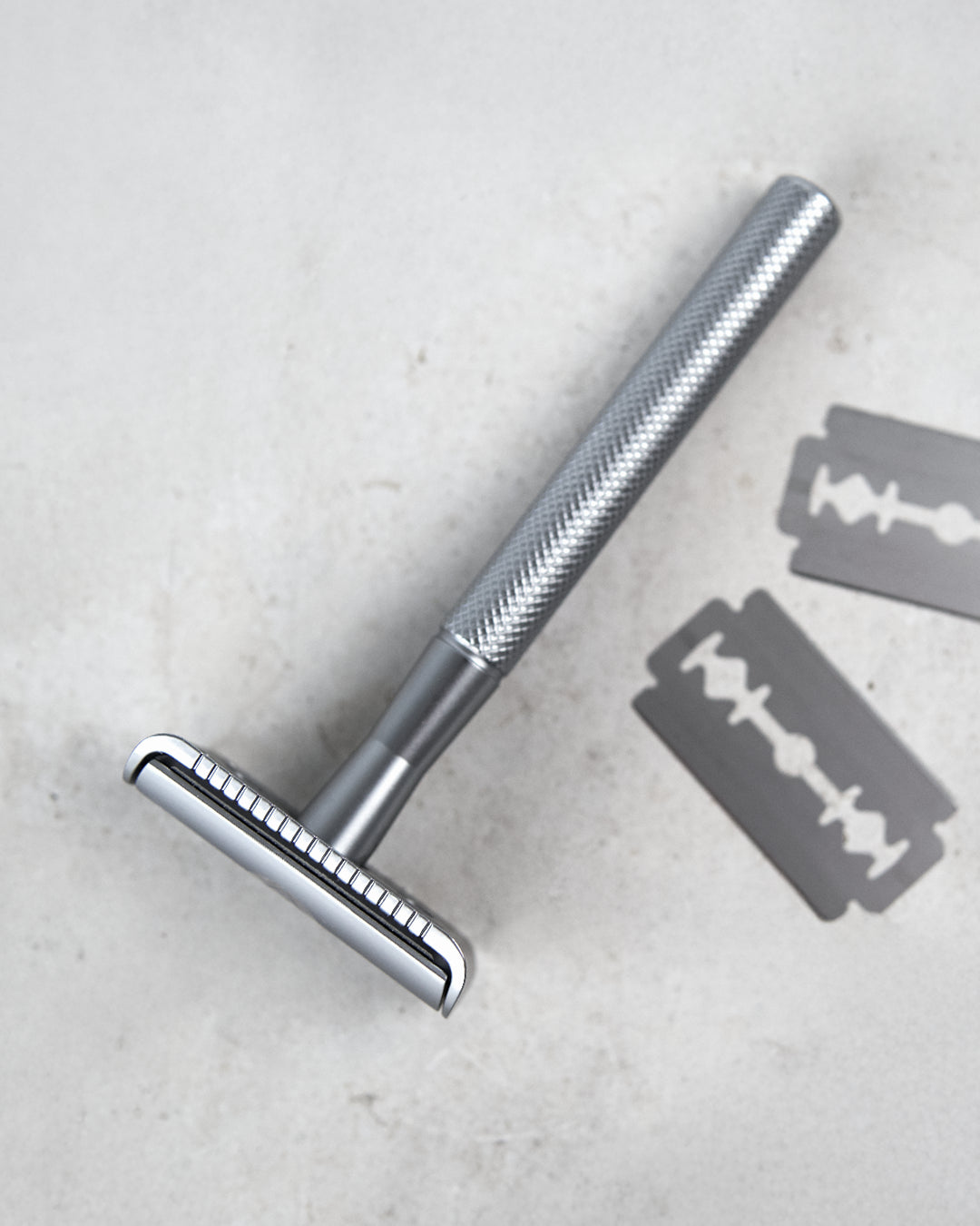 Silber Rasierer mit strukturierter Griffoberfläche auf grauem Hintergrund.