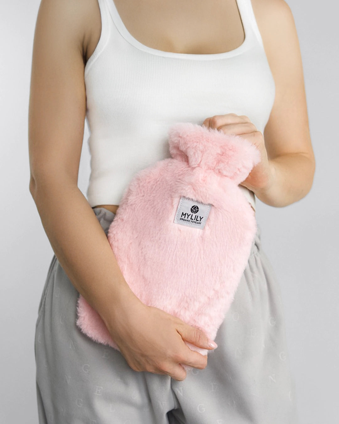 MYLILY Wärmflasche mit Bezug in sanftem Rosa. Gehalten von einer Person vor dem Körper