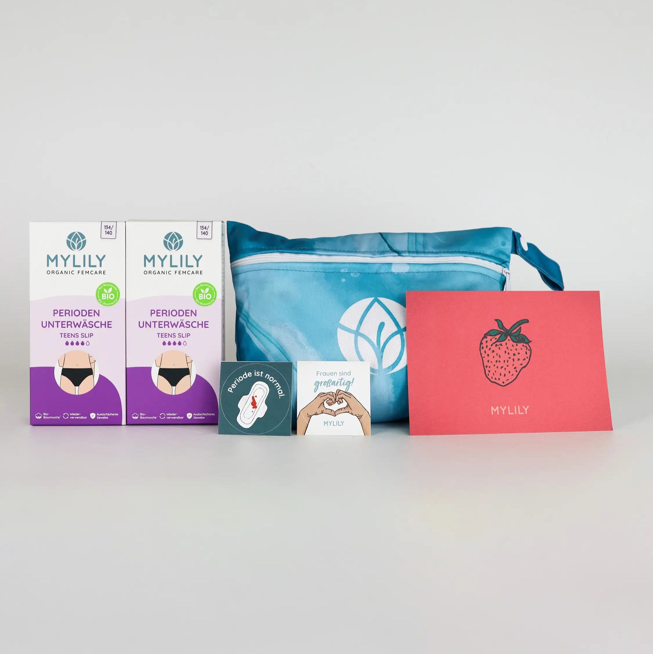 Inhalt des MYLILY Teens Period Panty Starter Set: 2 Periodenslips, 1 Wetbag, empwernde Sticker und eine Postkarte in rot mit Erdbeere